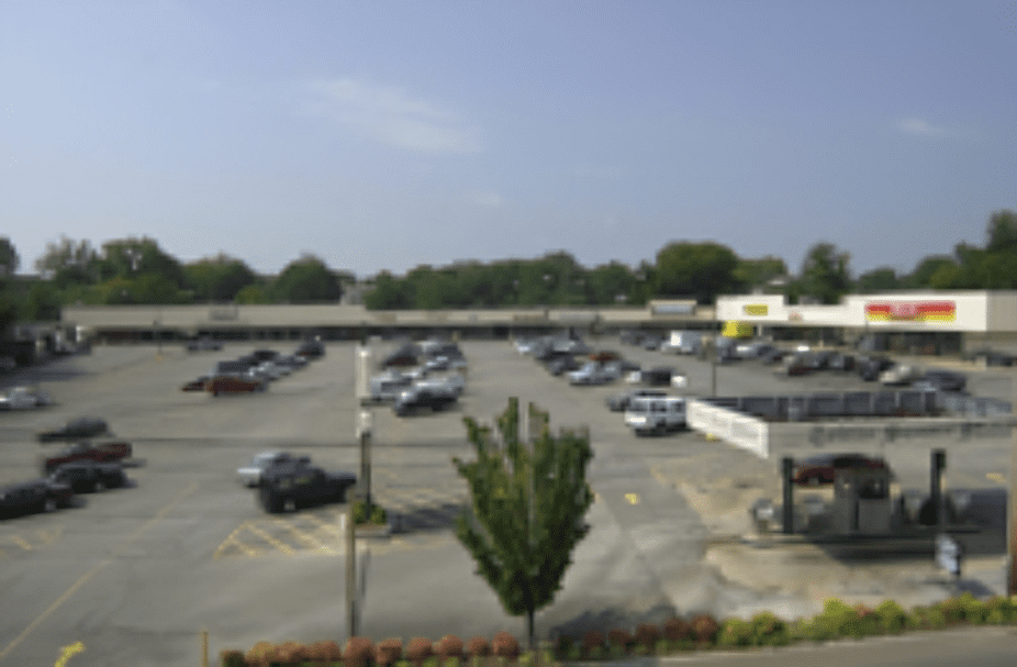 Shopping center parking lot with parked cars.