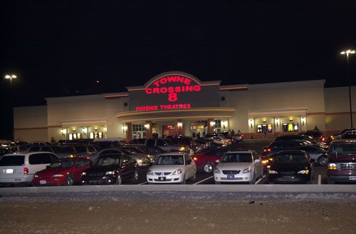 Movie theater with cars parked at night.