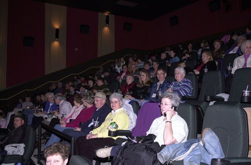Audience seated in a theater, watching attentively.
